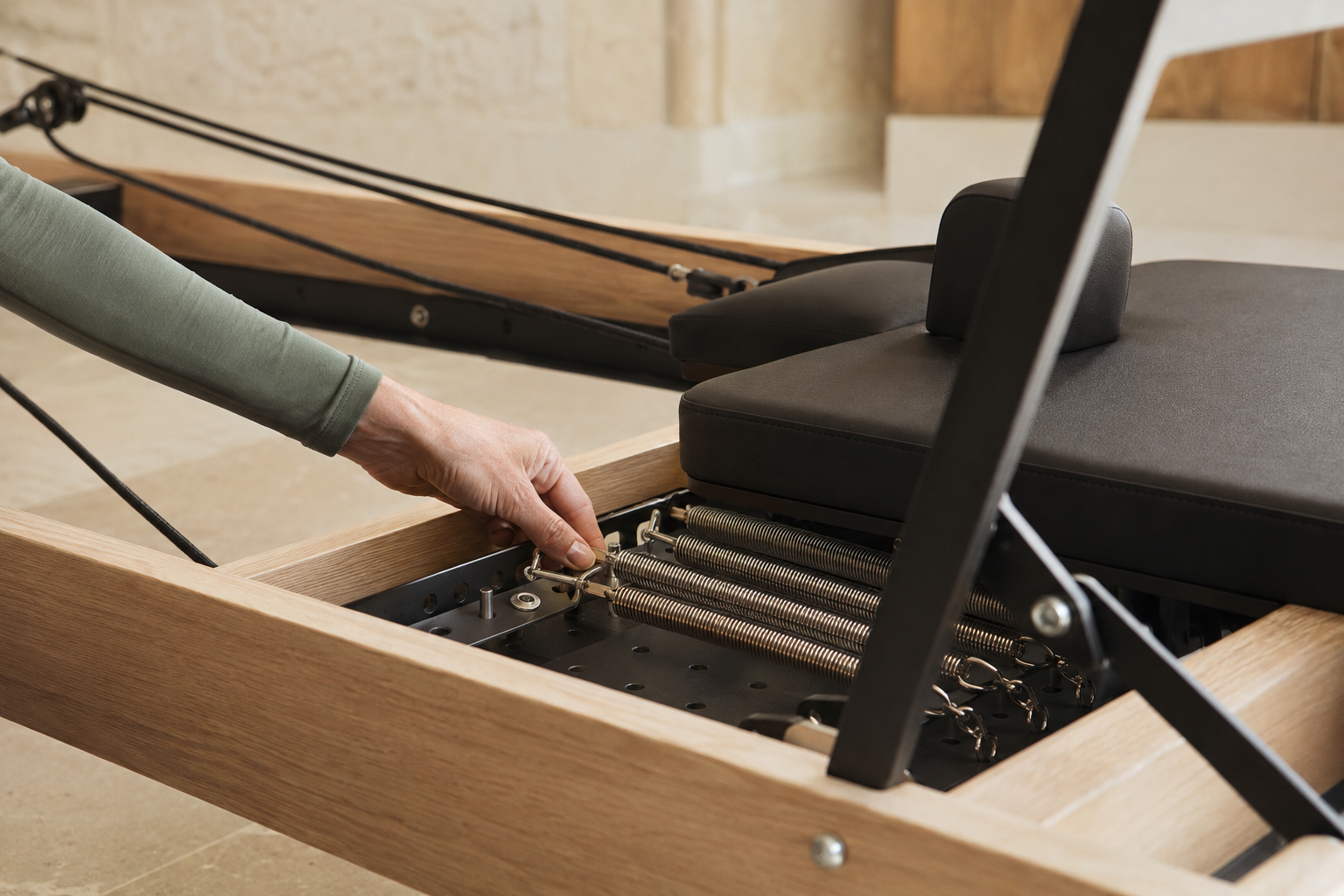 A careful spring adjustment on a professional Pilates reformer